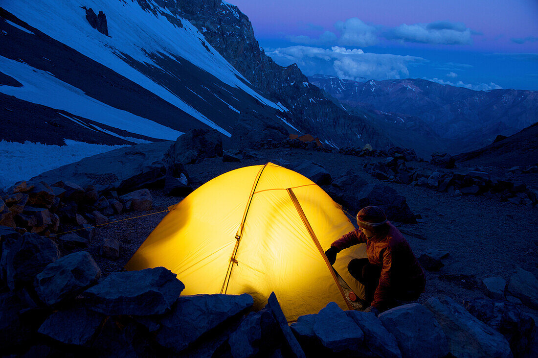 Woman unzips her tent at Camp One on Aconcagua in the Andes Mountains, Mendoza Province, Argentina