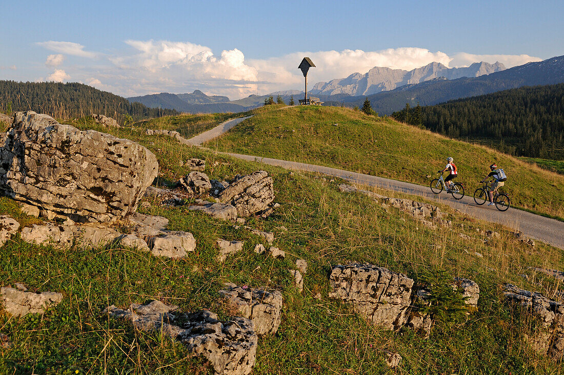 Couple riding e-bikes to Winklmoosalm, Reit im Winkl, Chiemgau, Upper Bavaria, Germany