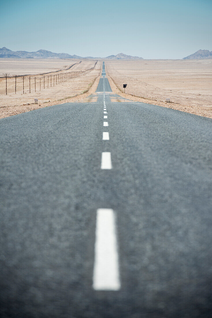 Tarmac road and endless row of electricity pylons in the desert near Luderitz, Namibia, Africa