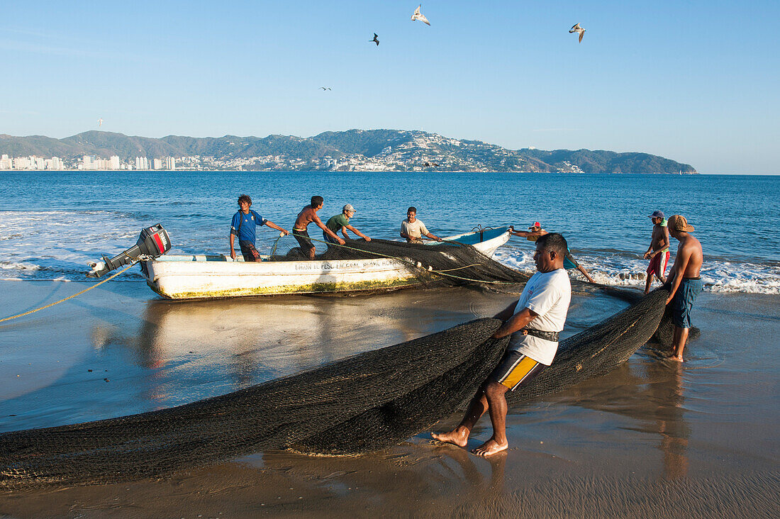 Fishermen carrying fishing nets, Playa Las Hamacas, Acapulco, Guerrero, Mexico
