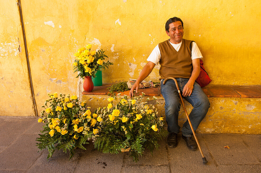 Man offering yellow roses in Plaza Mayor, Antigua, Sacatepequez, Guatemala