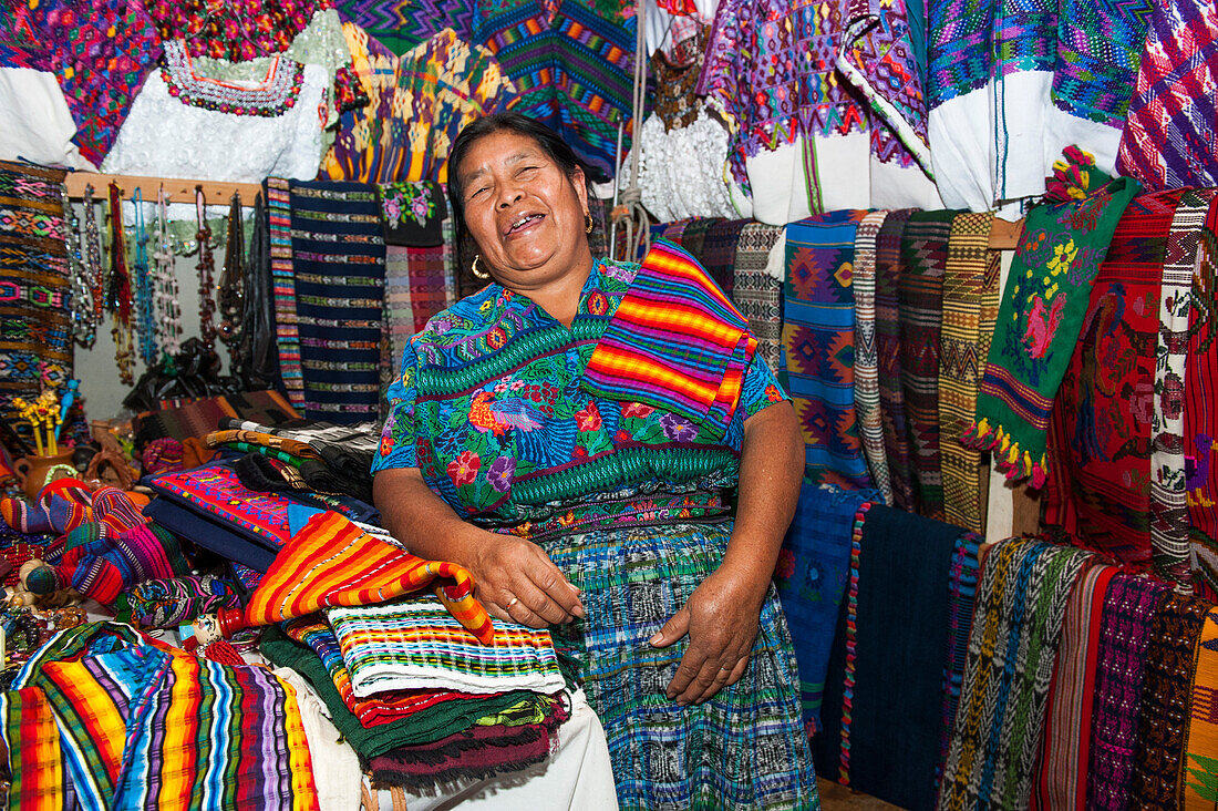 Woman offering colorful handicrafts at market stand, Antigua, Sacatepequez, Guatemala