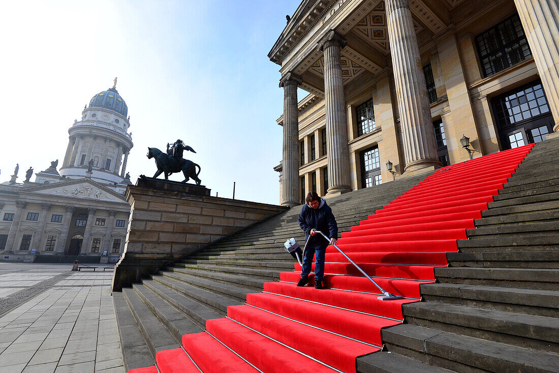 Person vacuuming the red carpet at the concert hall on Gendarmenmarket in Berlin Mitte, Berlin, Germany