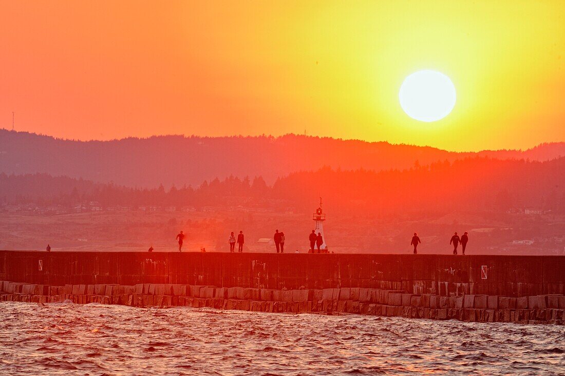 Breakwater wall with evening strollers at sunset, Victoria, British Columbia, Canada.
