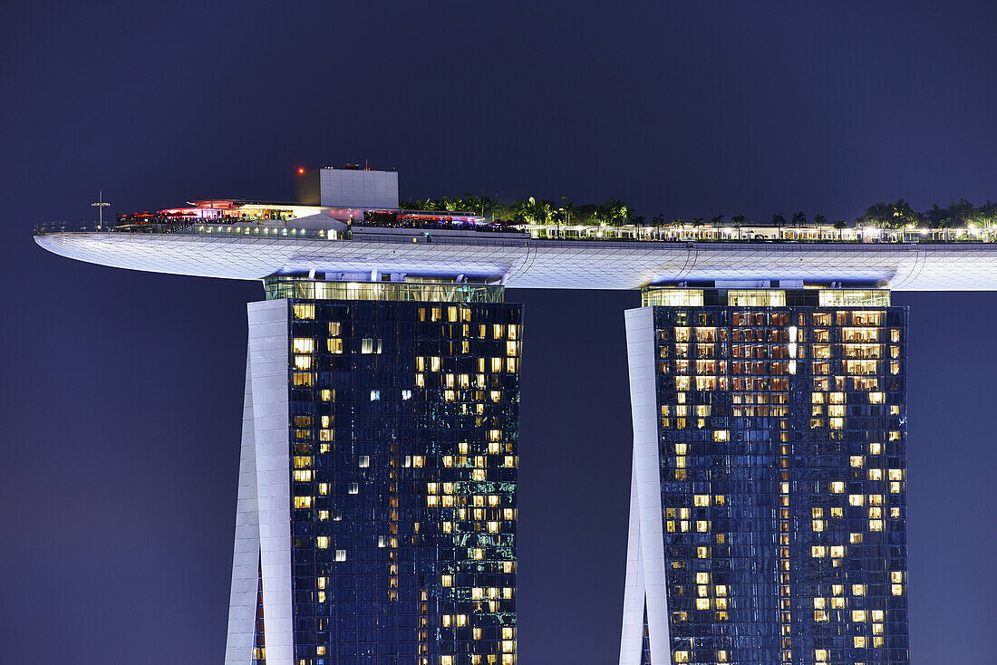 Marina Bay Sands Skypark at night. The SkyPark is a partially suspended rooftop deck, located on the top of Marina Bay Sands Hotel, that include a swimming pool, a bar, an obervation deck and a restaurant. Singapore.