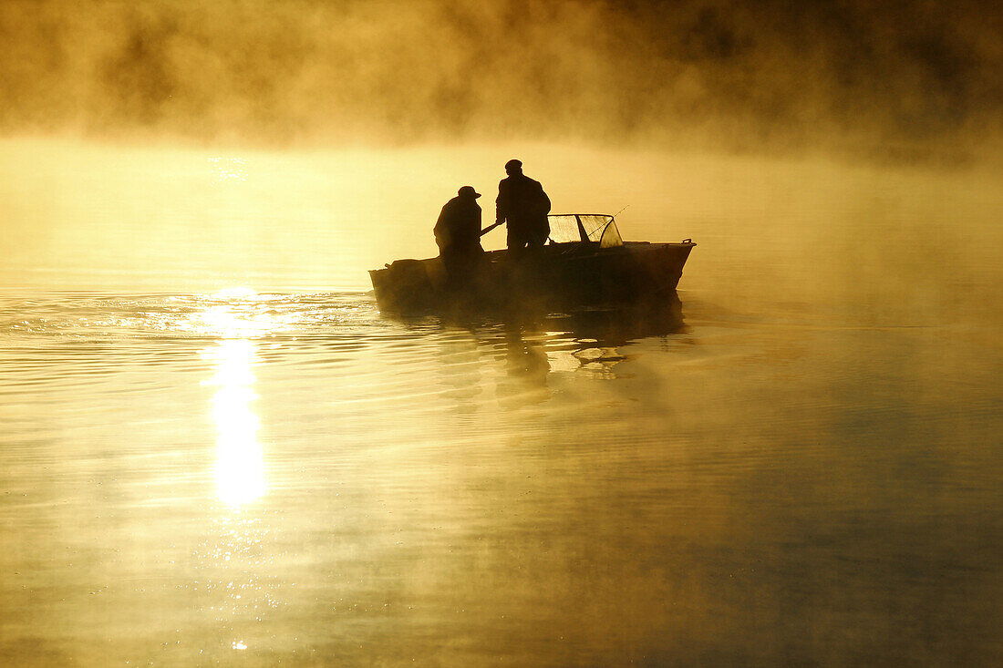 Two fishermen in the Finnish Gulf, sunrise. Primorsk, Russia.