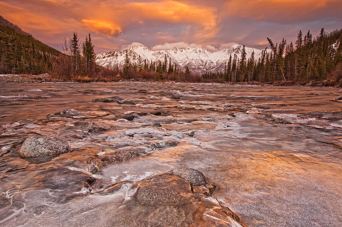 The Wheaton River In Early Winter With The Clouds Lit By Sunset Light. Snow Covered Mountains Seen In The Distance. Located Outside Of Whitehorse, Yukon.