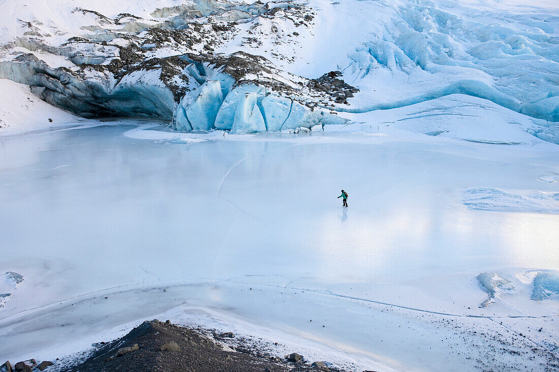 Woman Ice Skating In Front Of Saddlebag Glacier, Chugach Mountains Near Cordova, Southcentral Alaska, Winter