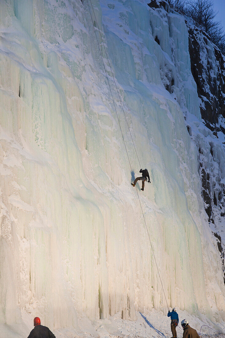 Evening Light Shines On An Ice Climber As He Repels Down An Ice Waterfall Along Turnagain Arm, Southcentral Alaska, Winter