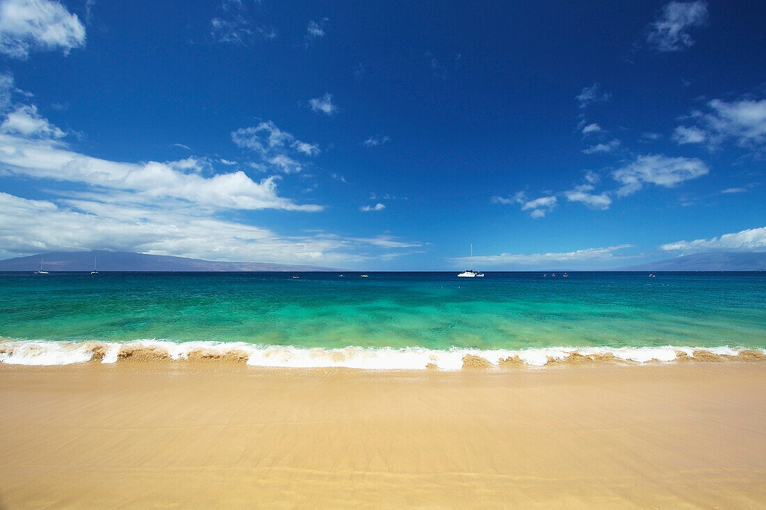 'A boat mooring in the water in the distance as viewed from the beach on the coast of an hawaiian island; Hawaii, United States of America'