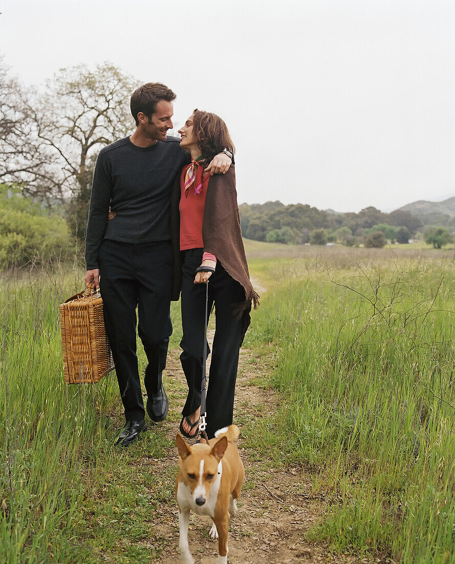 Couple with picnic basket walking dog