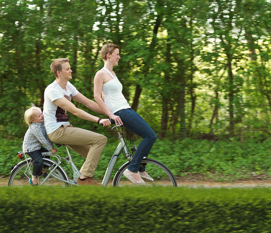 Family with one child riding on bicycle together