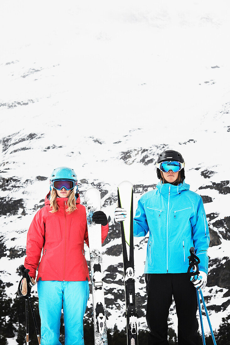 Young people wearing skiwear carrying skis