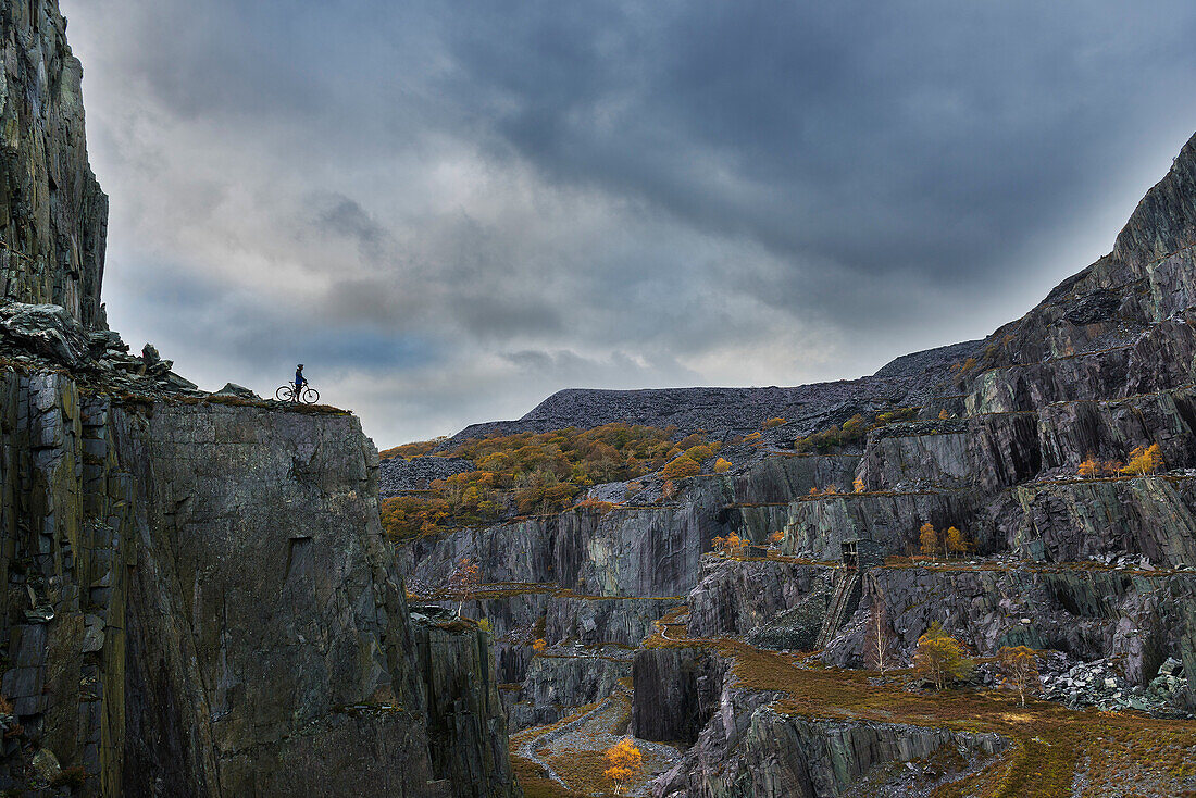 Freestyle cyclist on top of cliff, Llanberis, North Wales, UK