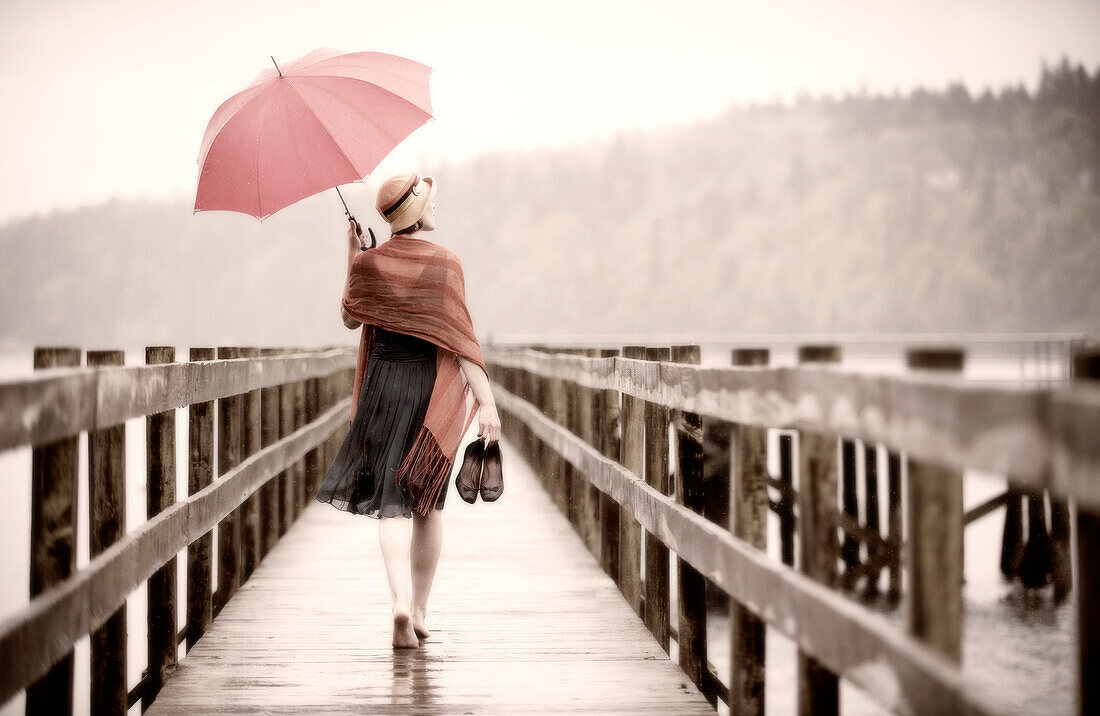 Woman with pink umbrella strolling on pier, Bainbridge Island, Washington, USA