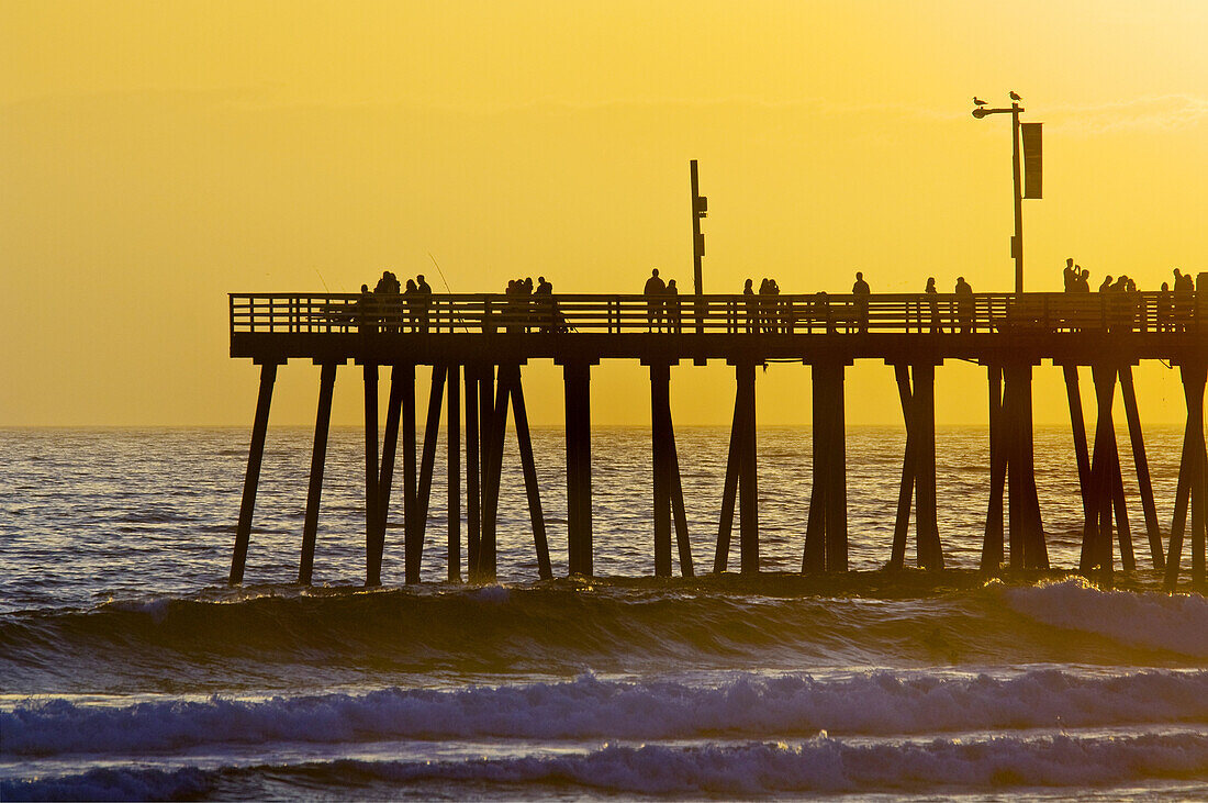 Sunset light over the pier and ocean waves at Pismo Beach, San Luis Obispo County coast, California.