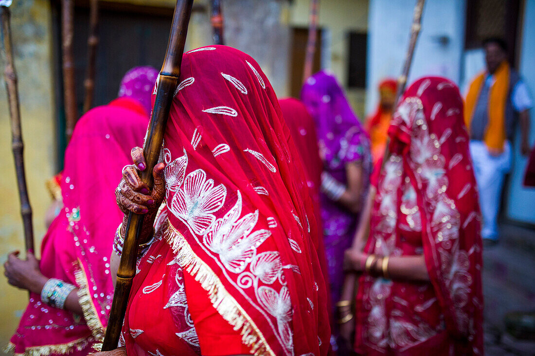 Women in colored clothes waits for men to be beaten with sticks during Lathmar Holi in the streets of Nandgaon, India