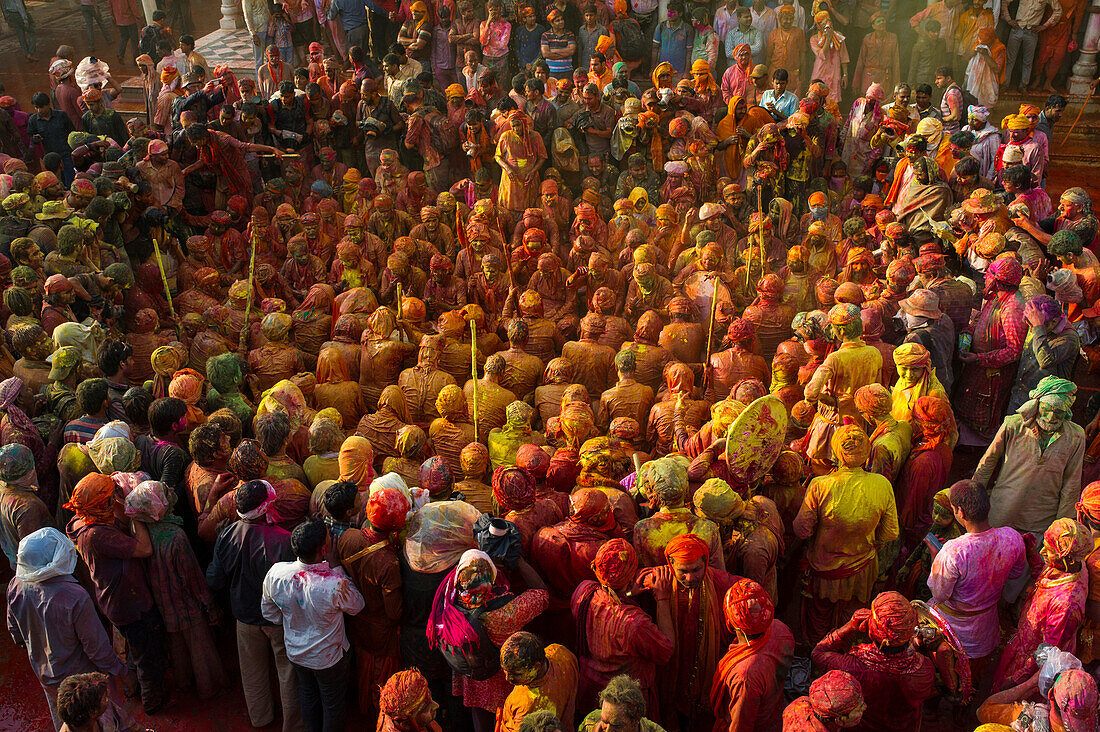 Men in red and yellow hue in the temple of Nandgaon during celebration of the Holi festival, Nandgaon, India