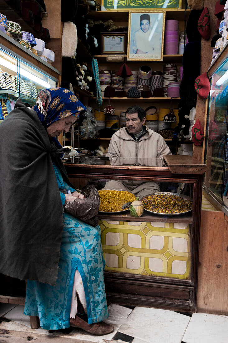 Man and a old woman in a typical spice shop of the suk of the medina in Fes, Morocco