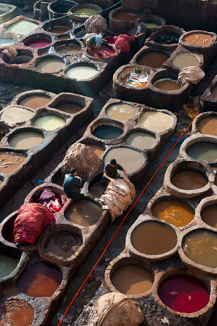 Workers painting leather in the colorful tanneries of Fes, Morocco