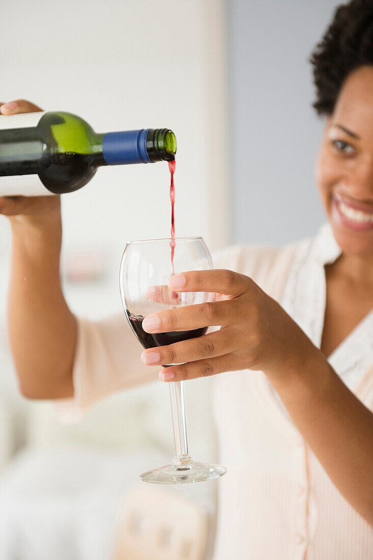 Black woman pouring glass of red wine, Jersey City, New Jersey, USA