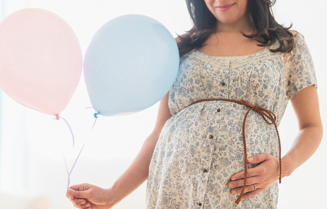 Pregnant Hispanic woman carrying balloon, Jersey City, NJ, USA