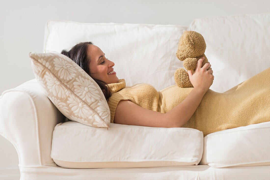 Pregnant Hispanic woman admiring teddy bear, Jersey City, NJ, USA