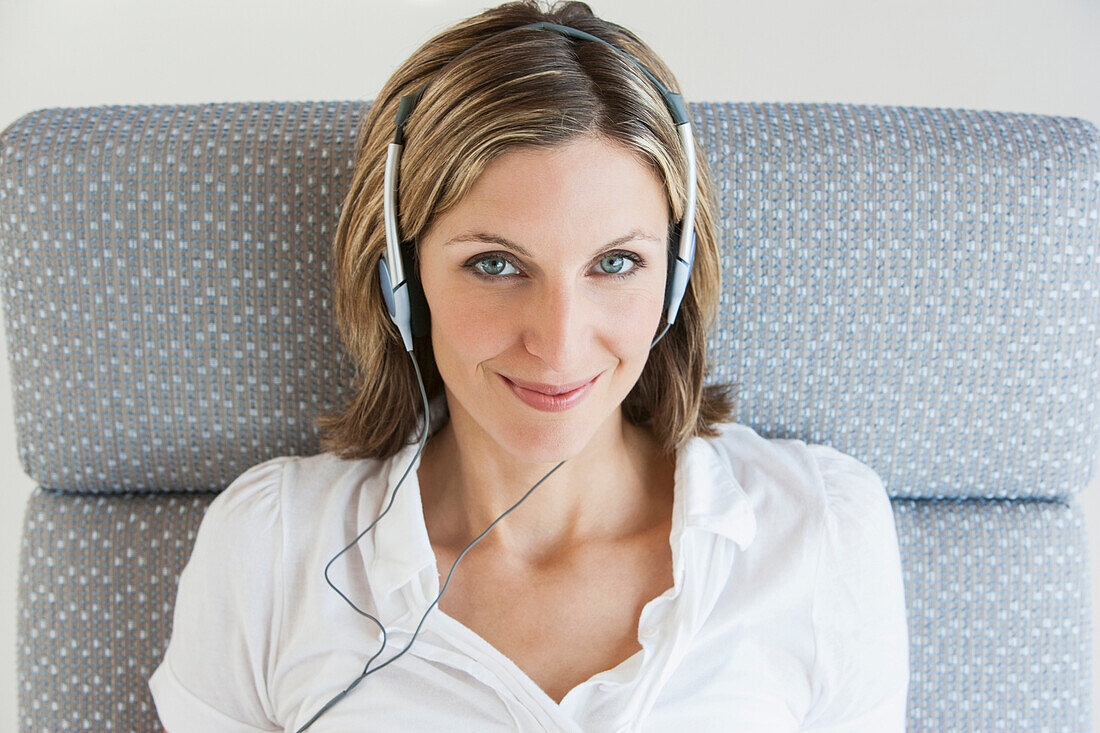 Woman listening to headphones in armchair, Palma de Mallorca, Balearic Islands, Spain