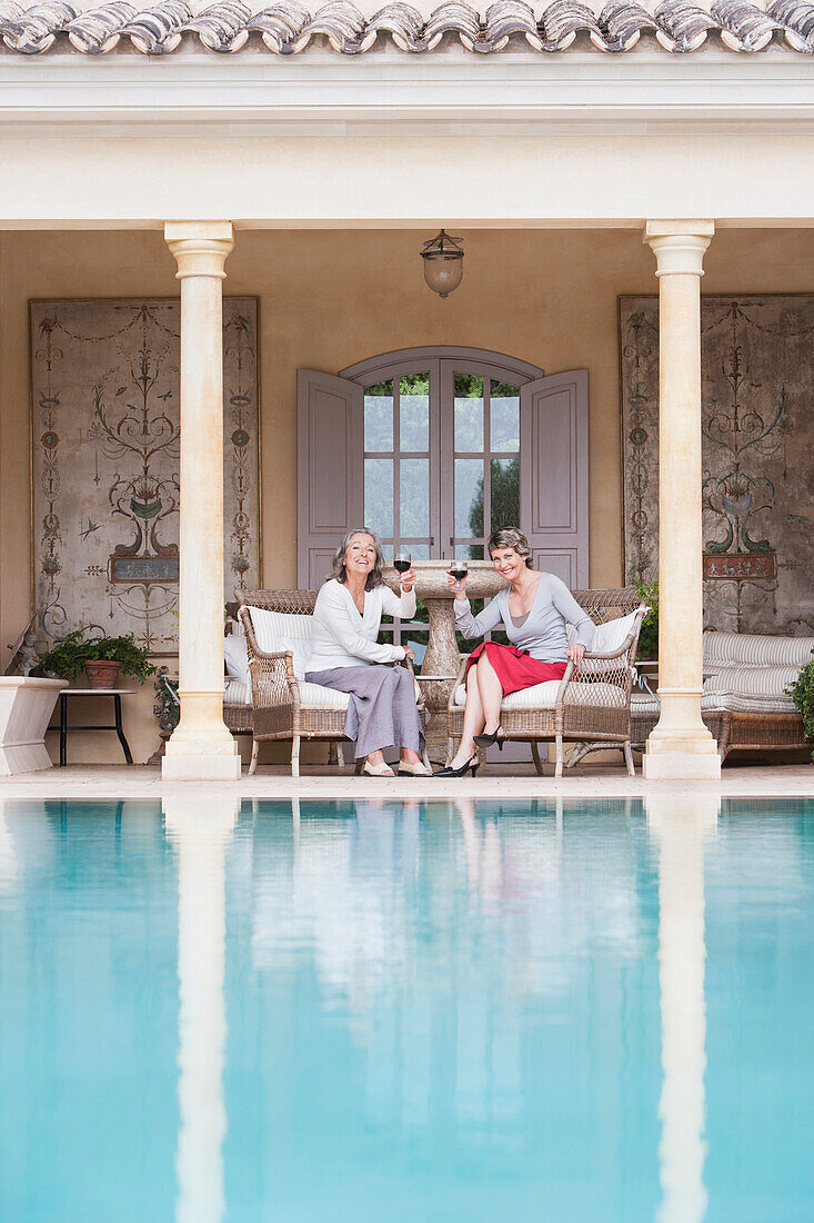 Women toasting each other by swimming pool, Palma de Mallorca, Balearic Islands, Spain