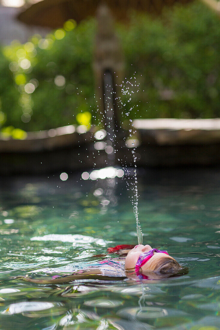 Caucasian girl spraying water in swimming pool, Ubud, Bali, Indonesia
