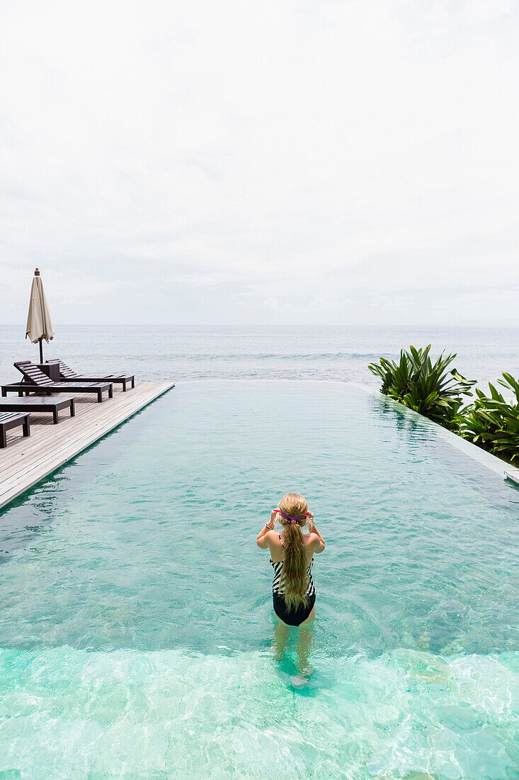 Caucasian girl swimming in infinity pool, Candidasa, Bali, Indonesia