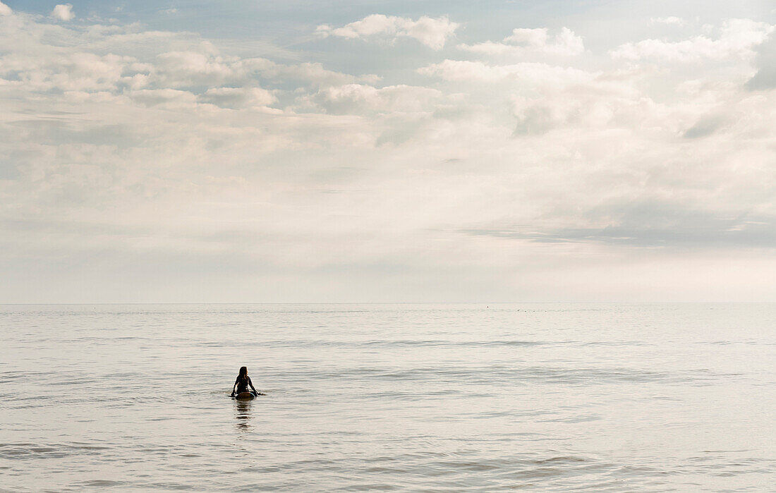 Hispanic surfer floating in water, Virginia Beach, VA, USA