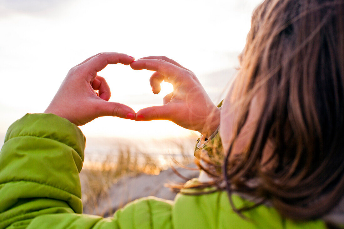 Caucasian girl admiring sunset through hands, Cannon Beach, Oregon, United States