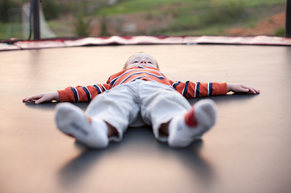 Caucasian boy laying on trampoline, Charlottesville, VA, USA