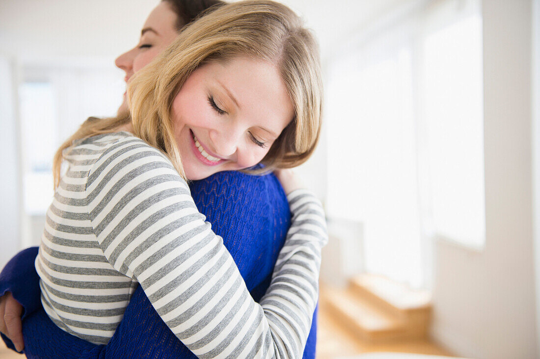 Women hugging in living room, Jersey CIty, New Jersey, USA
