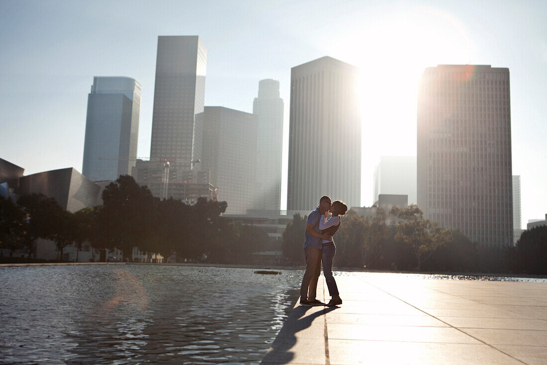 Couple kissing by urban waterfront, Los Angeles, CA, USA