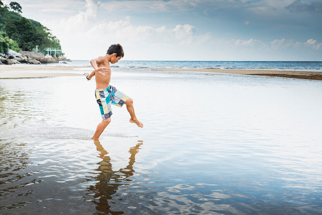 Mixed race boy playing in water on beach, Nayarit, Riviera Nayarit, Mexico