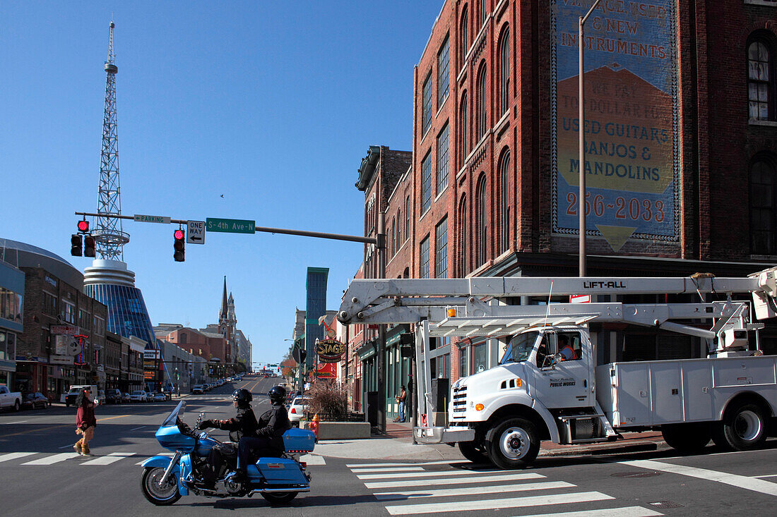 motorbike and truck crossing Broadway, visitor center tower in the background, Nashville, Tennessee, USA