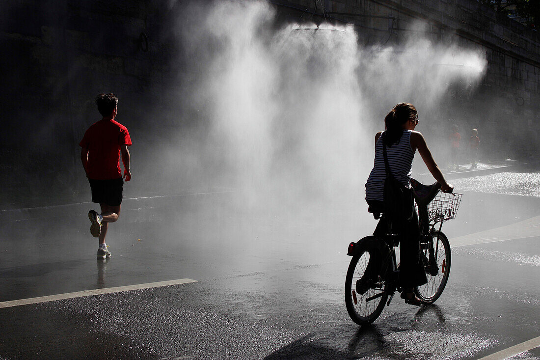 France, Paris at summer, jogger and cyclist under spray along the Seine river