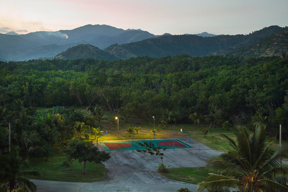 'Basketball Court Illuminated With Lights At Dusk With Mountains In The Background; Santiago Province, Cuba'