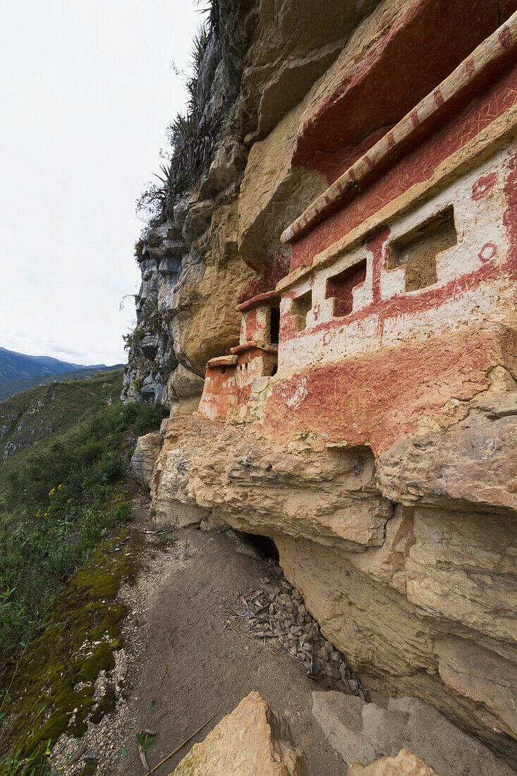 T-shaped windows in a chullpa (stone tomb chamber) of the Chachapoya culture with walls colored with red figures, nestled in the limestone cliffs of Cerro Carbón overlooking the Utcubamba River, Revash, Amazonas, Peru