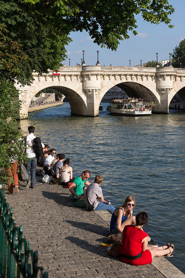 Relaxing and picnicking on the quays of the seine and ile de la cite with the pont neuf bridge in front of the square du vert galant, quay of the louvre, paris (75), france