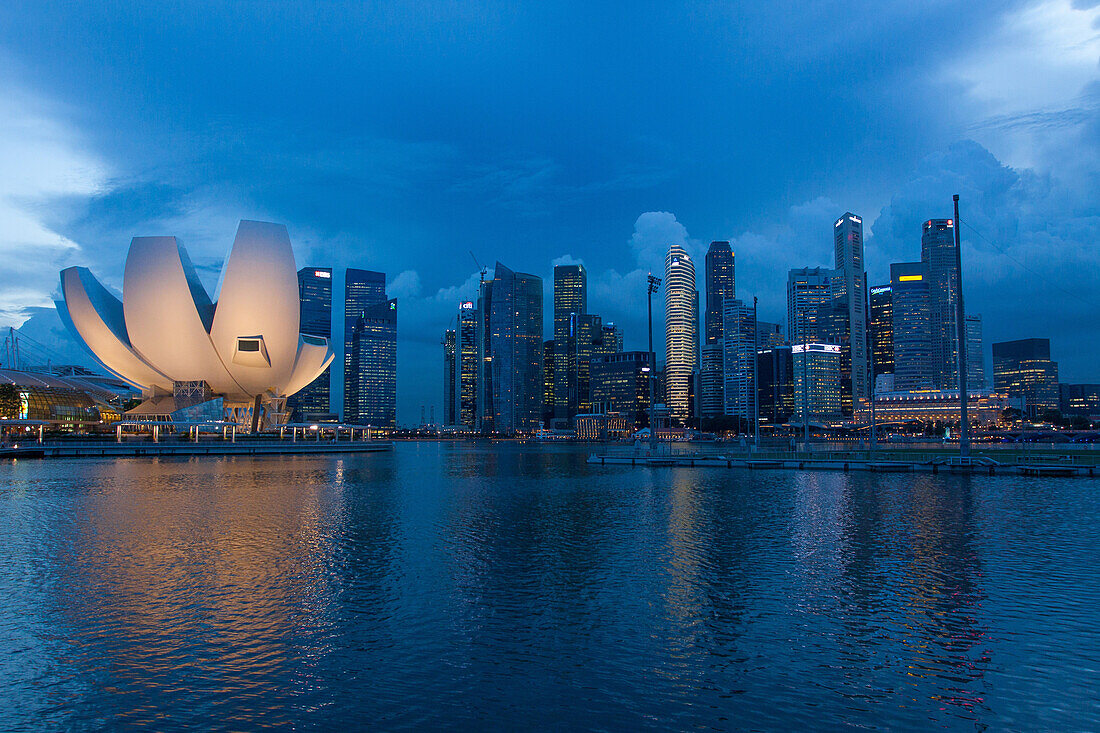 Night falling over marina bay, the lotus flower-shaped dome of the art science museum and the buildings in the central business district, singapore