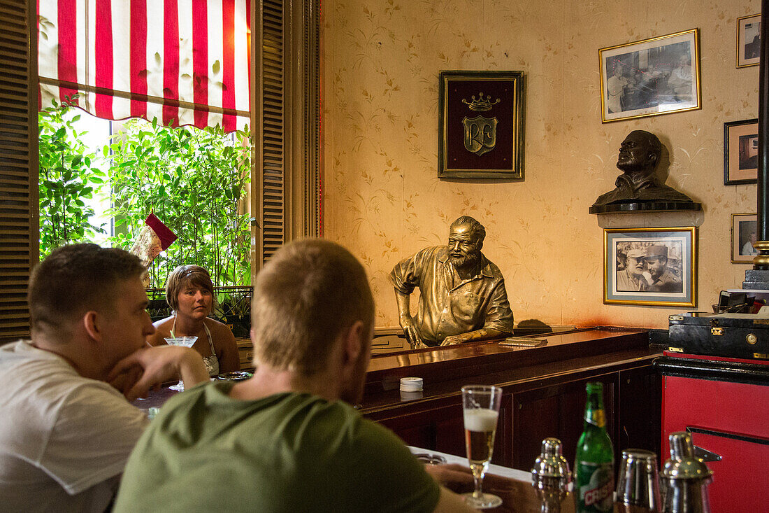 Statue and photos of ernest hemingway (1899-1961), american author and journalist, in the bar el floridita where he drank his favorite daiquiri, calle del obispo, habana vieja, havana, cuba, the caribbean