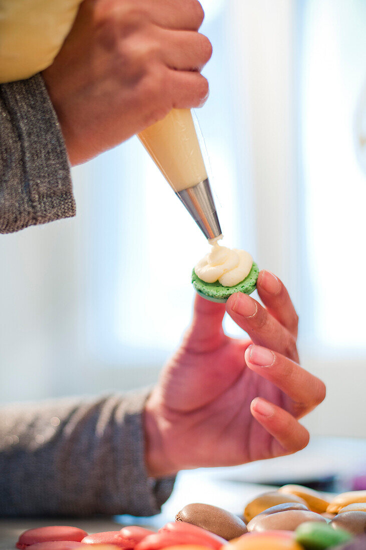 Woman Putting Icing on Macaroon Cookie, Close-Up