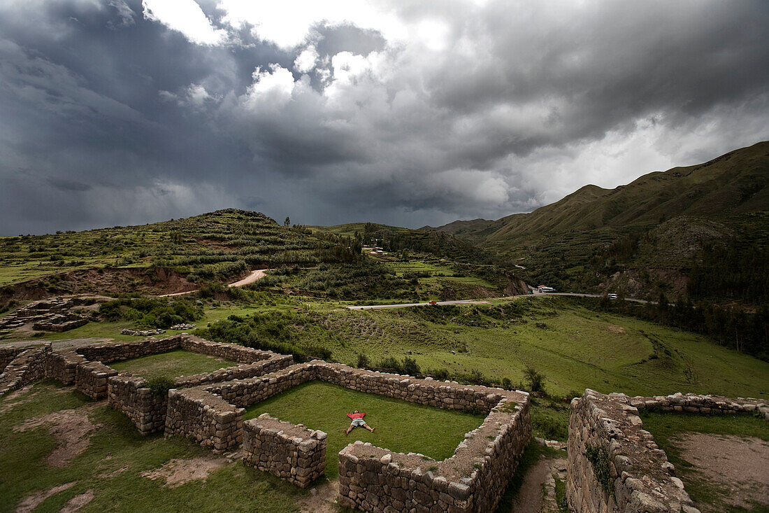 A Person Meditates In Ancient Incan Ruins Outside Cuzco, Peru