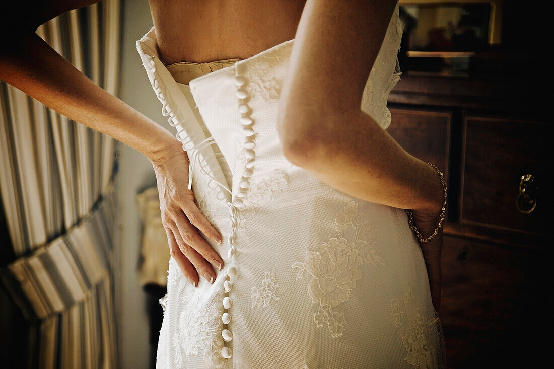 A Woman Fastening The Back Of Her Wedding Dress