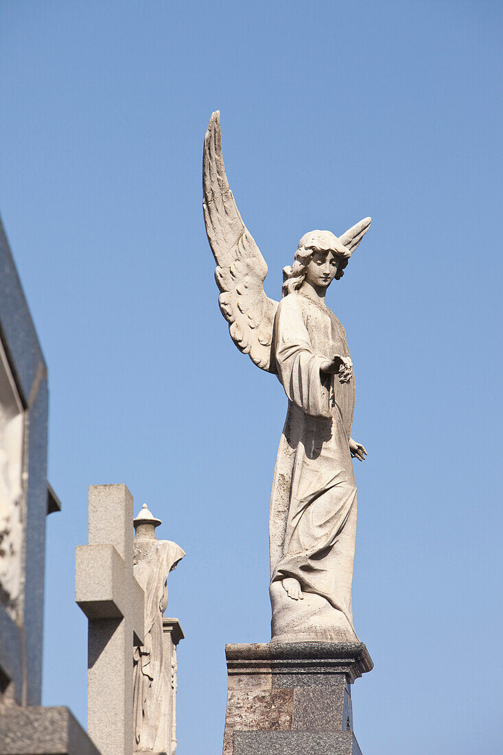'Buenos Aires, Argentina; Angel Statues And A Cross Made Of Stone On Top Of Tombs In The Recoleta Cemetery'