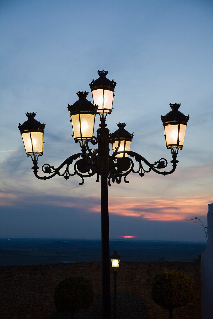 'Medina Sidonia, Andalusia, Spain; A Light Post With 5 Lamps On It Illuminated At Night'