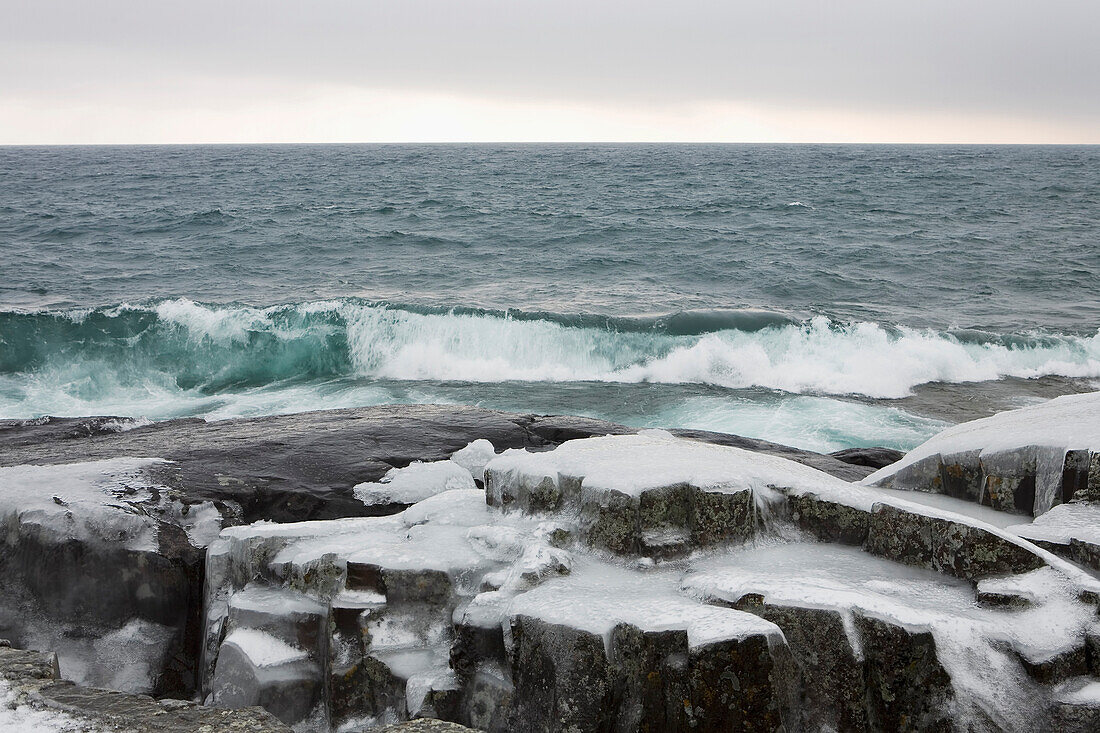 'Grand Marais, Minnesota, United States Of America; Waves Crashing Against Ice Covered Rocks In Winter'